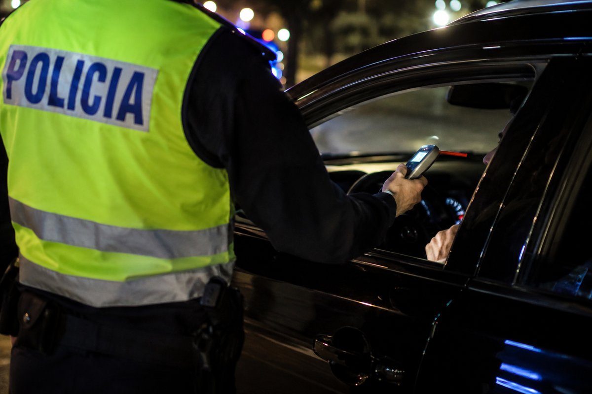 Agente de Policía realizando una prueba de alcoholemia con etilómetro a un conductor de noche, caso de absolución por conducción bajo la influencia del alcohol